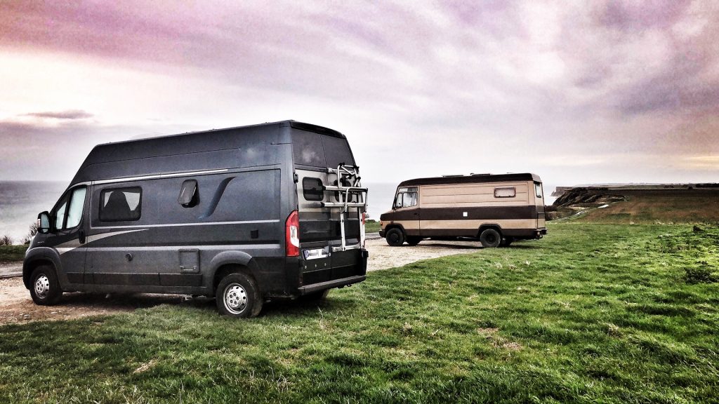 Zwei Vans stehen nebeneinander auf einem Stellplatz an der Steilküste